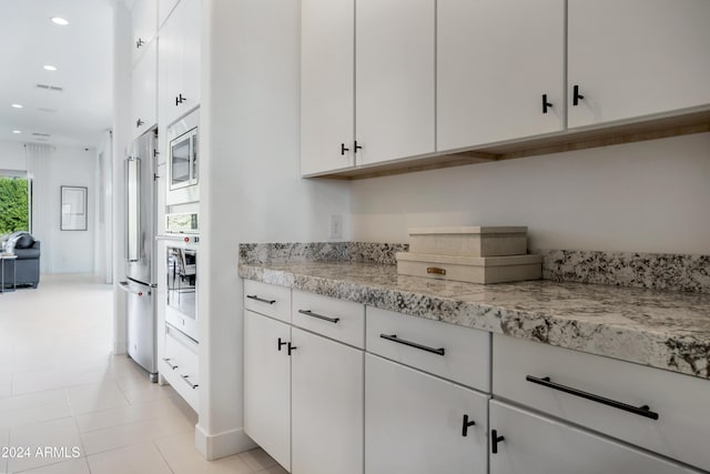 kitchen with white cabinets, light tile patterned flooring, and appliances with stainless steel finishes