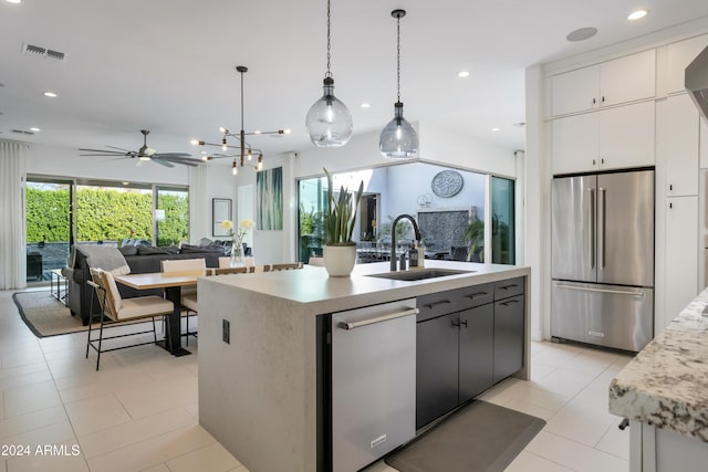 kitchen with sink, hanging light fixtures, stainless steel appliances, an island with sink, and white cabinets