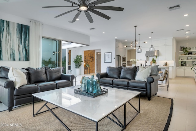 living room featuring light tile patterned flooring, ceiling fan, and sink