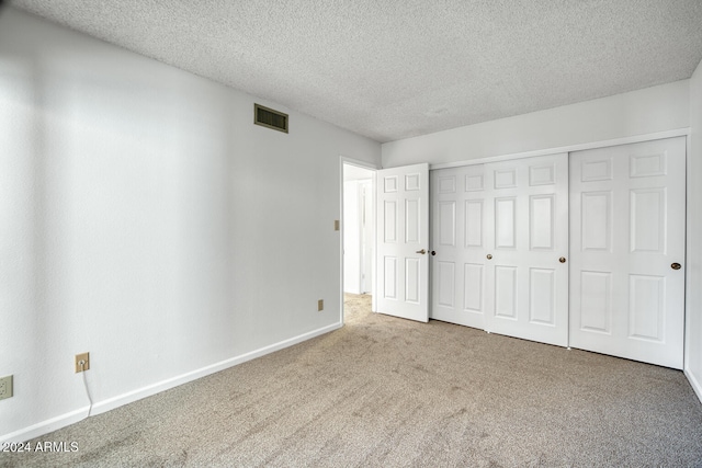 unfurnished bedroom featuring carpet flooring, a textured ceiling, and a closet