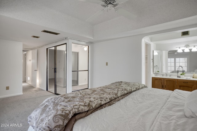 bedroom with ceiling fan, sink, light carpet, and a textured ceiling