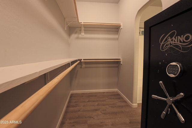 spacious closet with arched walkways and dark wood-style flooring