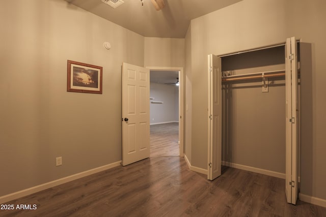 unfurnished bedroom with a closet, baseboards, and dark wood-style flooring