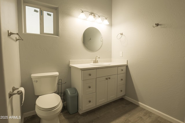 bathroom featuring vanity, wood finished floors, toilet, and baseboards