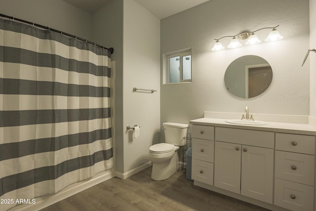 bathroom featuring baseboards, a shower with shower curtain, toilet, wood finished floors, and vanity