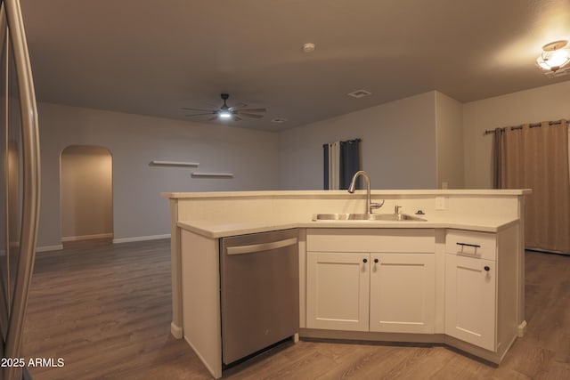 kitchen featuring stainless steel appliances, arched walkways, light countertops, and a sink