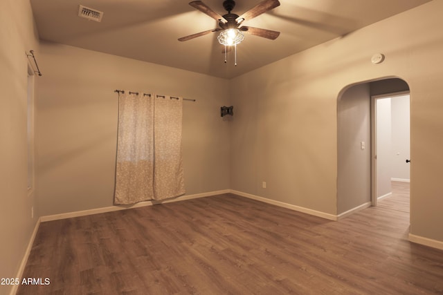 unfurnished room featuring arched walkways, visible vents, a ceiling fan, wood finished floors, and baseboards