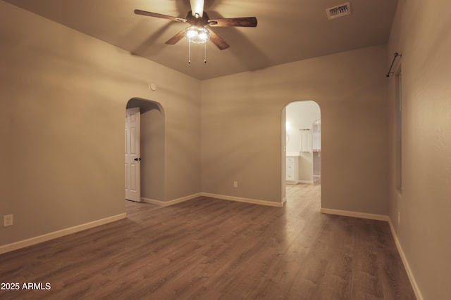 unfurnished room featuring baseboards, visible vents, arched walkways, ceiling fan, and wood finished floors