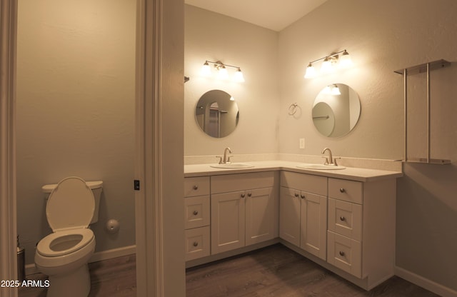 bathroom with toilet, baseboards, wood finished floors, and vanity