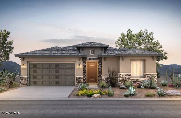 prairie-style house with an attached garage, a mountain view, stone siding, concrete driveway, and stucco siding