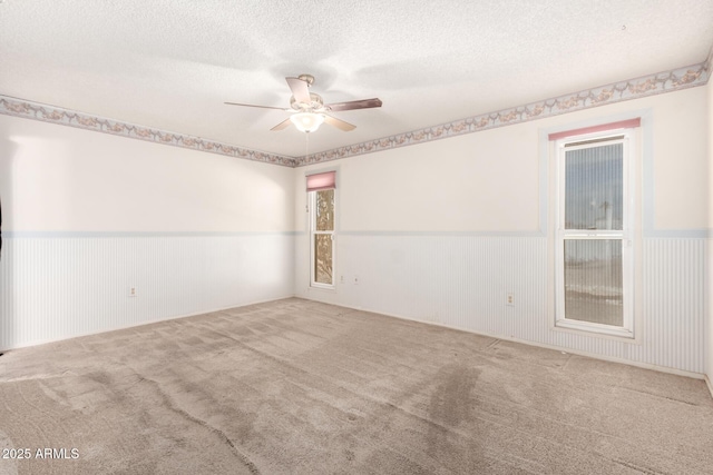 carpeted spare room featuring ceiling fan and a textured ceiling