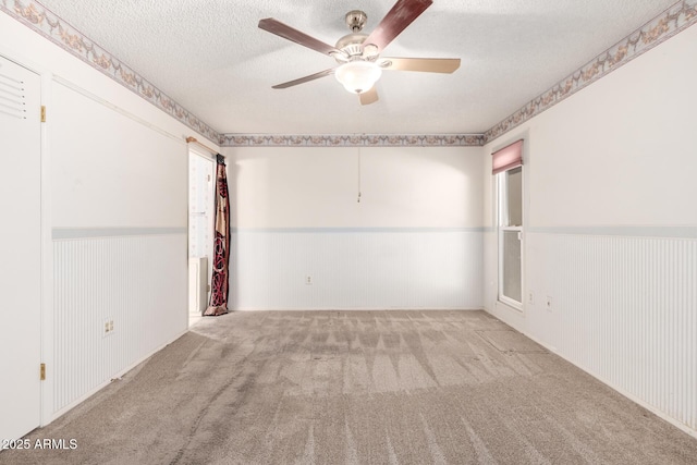 carpeted spare room featuring ceiling fan and a textured ceiling