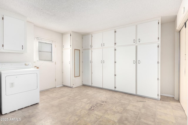 laundry area featuring cabinets, washer / dryer, and a textured ceiling