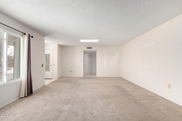 empty room with light carpet and a textured ceiling