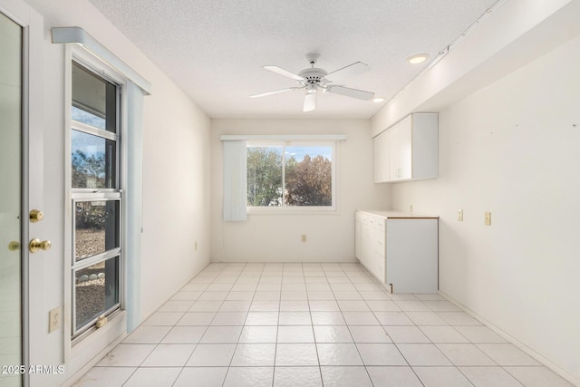 tiled empty room with ceiling fan and a textured ceiling