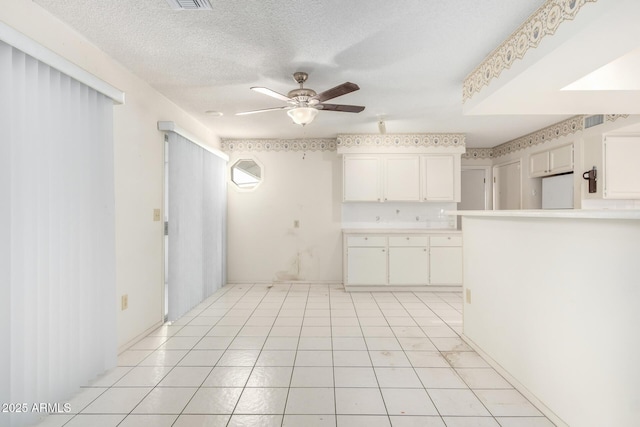 kitchen with white cabinetry, ceiling fan, a textured ceiling, and light tile patterned floors