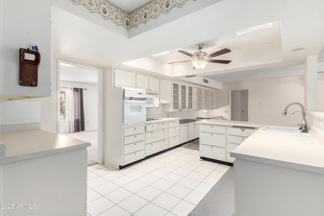 kitchen featuring sink, white appliances, a raised ceiling, and white cabinets