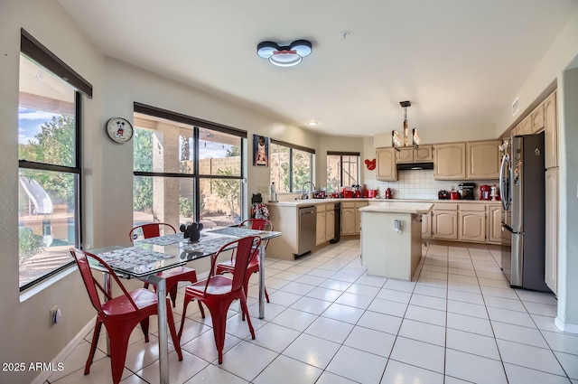 kitchen with a kitchen island, decorative backsplash, a healthy amount of sunlight, appliances with stainless steel finishes, and a chandelier