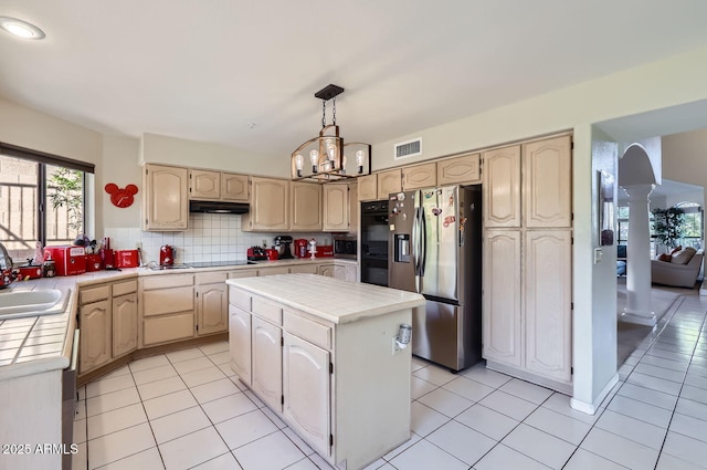 kitchen with tile countertops, appliances with stainless steel finishes, decorative backsplash, a chandelier, and a kitchen island