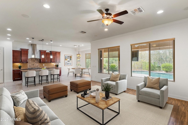 living area featuring recessed lighting, a ceiling fan, ornamental molding, light wood-style floors, and baseboards