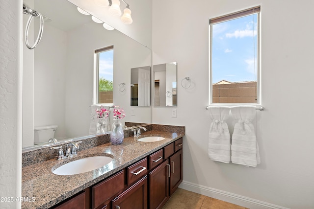 full bath with baseboards, toilet, double vanity, and tile patterned floors