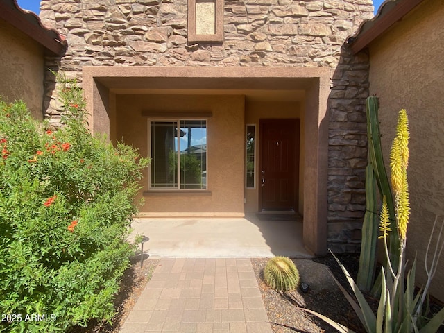property entrance with stone siding and stucco siding