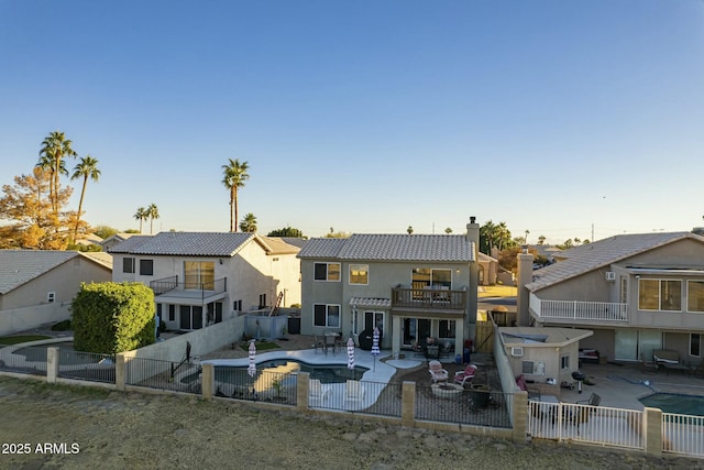 back of property with a fenced in pool, a patio area, and a balcony