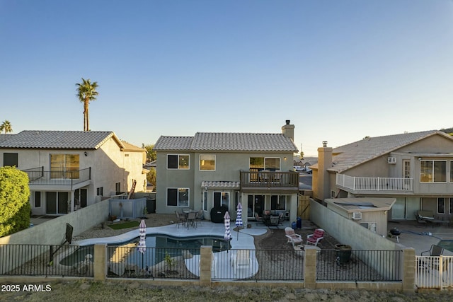 back of house with a fenced in pool, a patio area, and a balcony