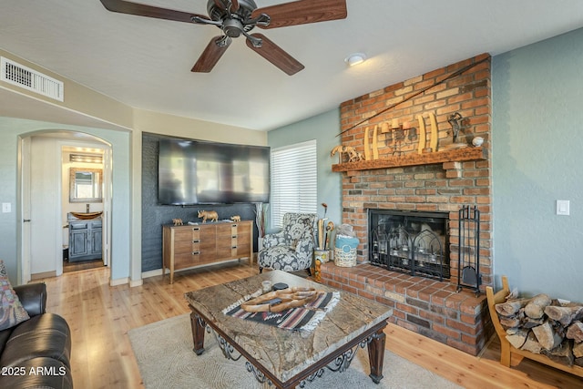 living room featuring ceiling fan, a brick fireplace, and hardwood / wood-style floors