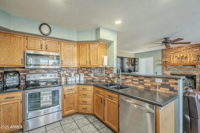 kitchen featuring ceiling fan, backsplash, kitchen peninsula, sink, and stainless steel appliances