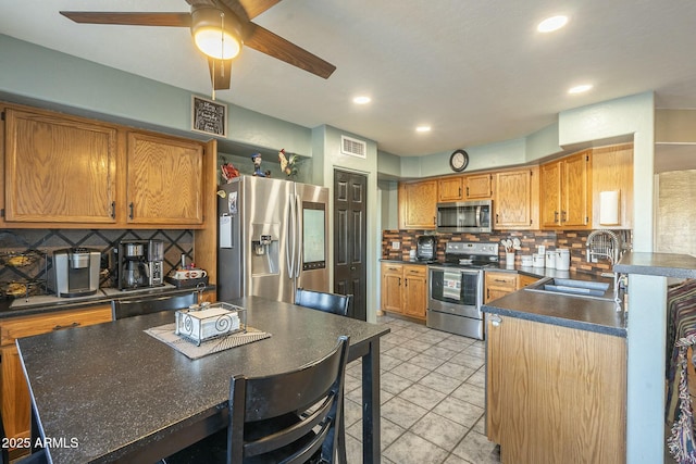 kitchen with light tile patterned floors, ceiling fan, stainless steel appliances, decorative backsplash, and sink