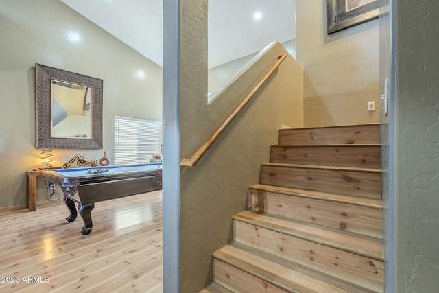 staircase featuring vaulted ceiling, hardwood / wood-style flooring, and billiards