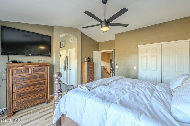 bedroom with ceiling fan, a closet, light wood-type flooring, and lofted ceiling