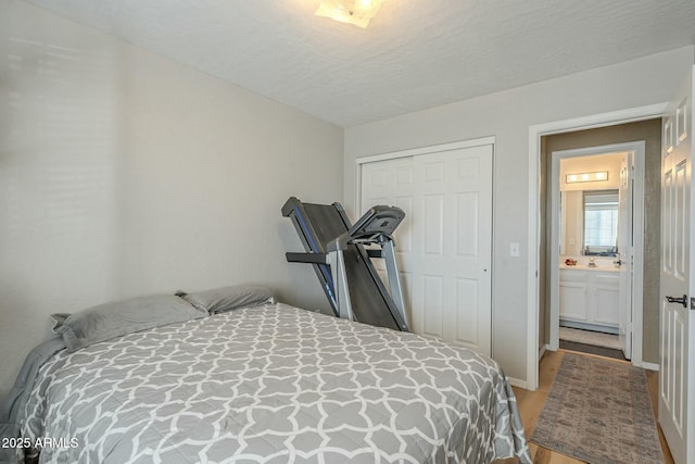 bedroom featuring a textured ceiling, a closet, connected bathroom, and hardwood / wood-style flooring