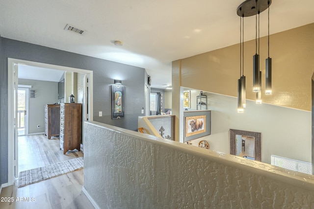 hallway with a healthy amount of sunlight and light hardwood / wood-style floors