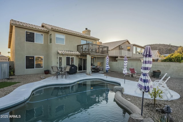 back of house featuring a fenced in pool, a balcony, and a patio