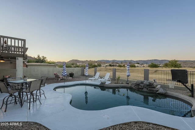 pool at dusk featuring a mountain view and a patio