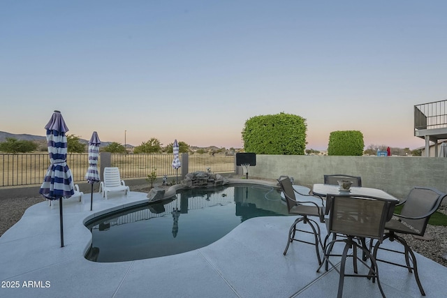 pool at dusk featuring a patio area