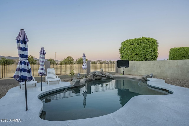 pool at dusk featuring a patio