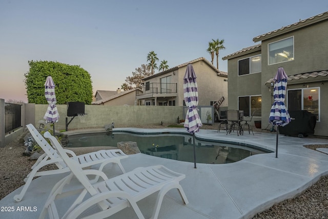 pool at dusk featuring a patio area