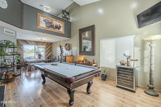 rec room featuring wood walls, a towering ceiling, light wood-type flooring, beverage cooler, and pool table