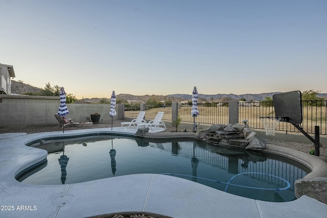 pool at dusk featuring a mountain view and a patio