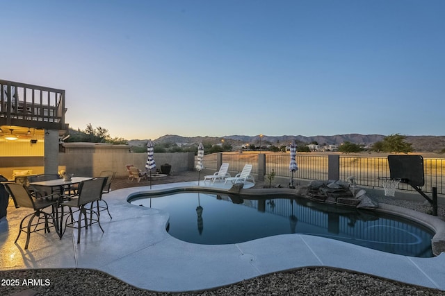 pool at dusk with a patio area and a mountain view