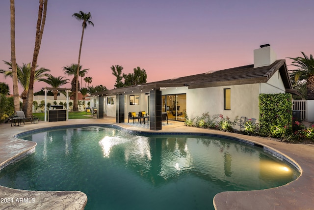 pool at dusk featuring a patio