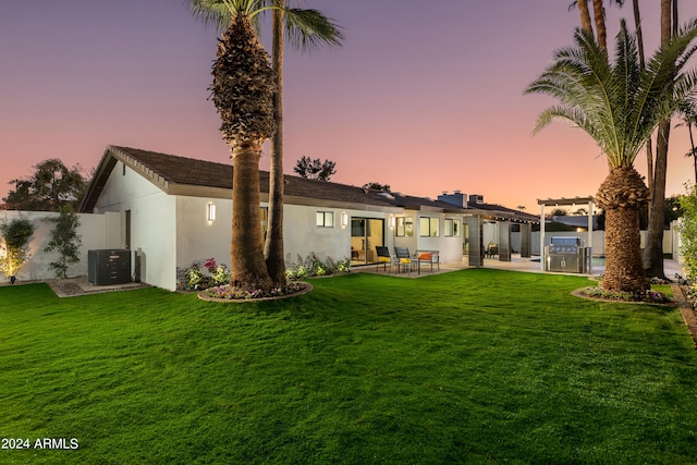 back house at dusk with a lawn, a patio, area for grilling, and central AC