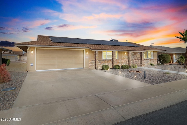 ranch-style home featuring solar panels and a garage