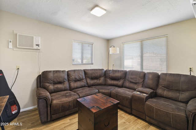 living room with a wall unit AC and light hardwood / wood-style flooring