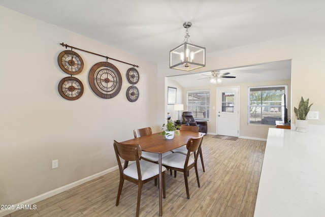 dining room with ceiling fan with notable chandelier and light hardwood / wood-style floors