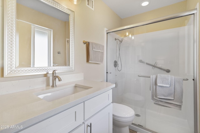 bathroom featuring toilet, vanity, and a shower with shower door