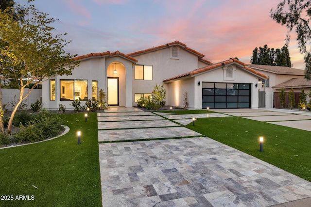 mediterranean / spanish-style home with a yard and a garage